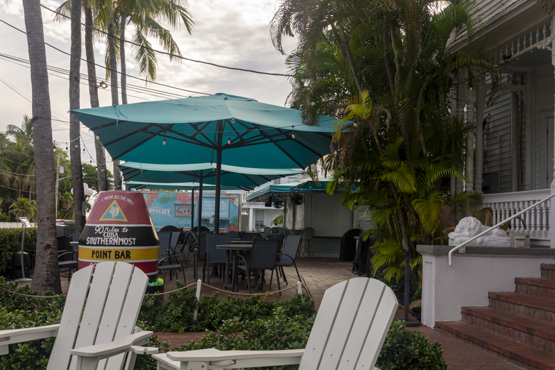 Outdoor patio at Southernmost Point Bar in Key West, Florida, with turquoise umbrellas and seating.